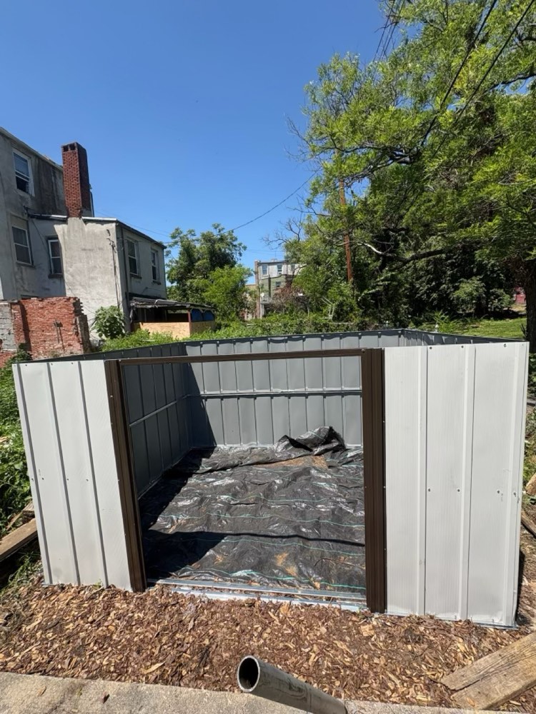 A newly built garden shed on a fresh bed of wood chips under a clear blue sky